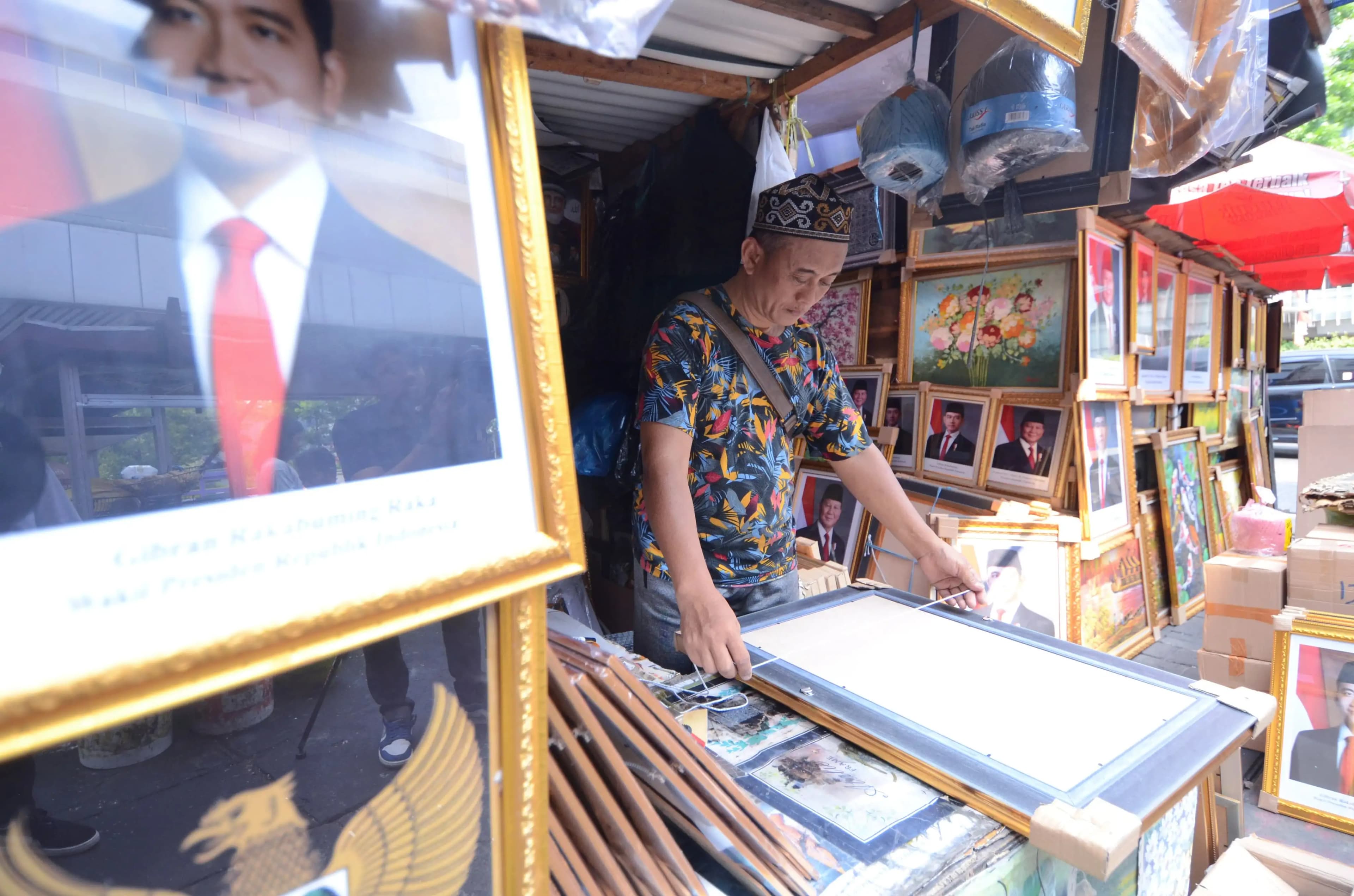 Pedagang mengukur bingkai foto presiden Prabowo Subianto (Foto: Dok MI/Donavita)