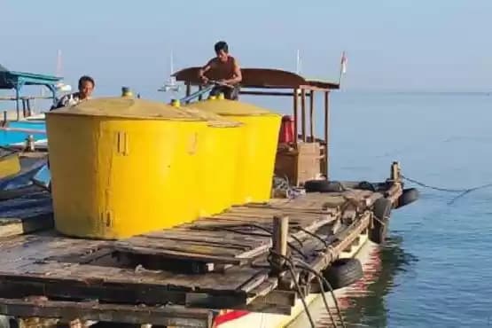 Foto Warga dari atas perahu tongkang memindahkan air bersih