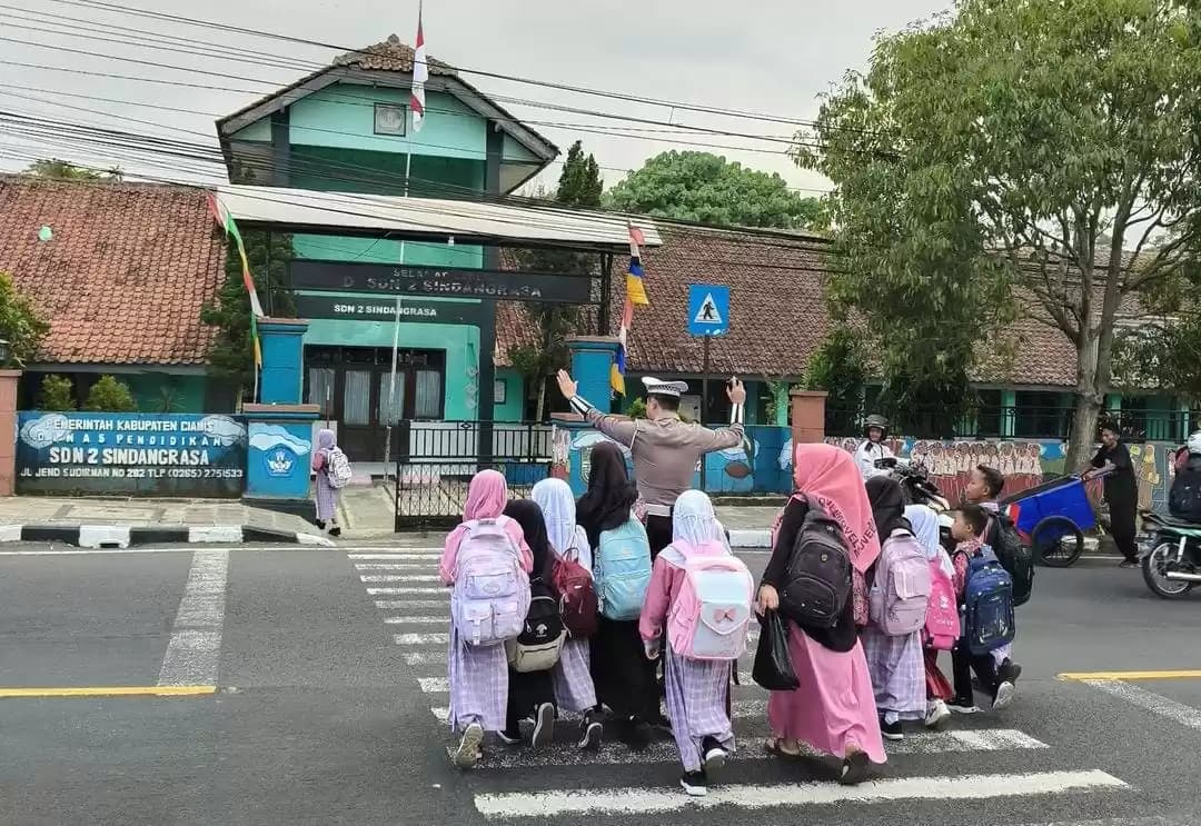 Momen Personel Satlantas Polres Ciamis saat Membantu Siswa-siswi Menyebrangi Jalan. (Foto: @tmcpolresciamis).