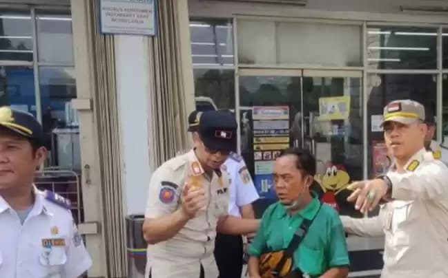 Petugas menertibkan seorang juru parkir liar di sebuah tempat usaha ritel, Kembangan