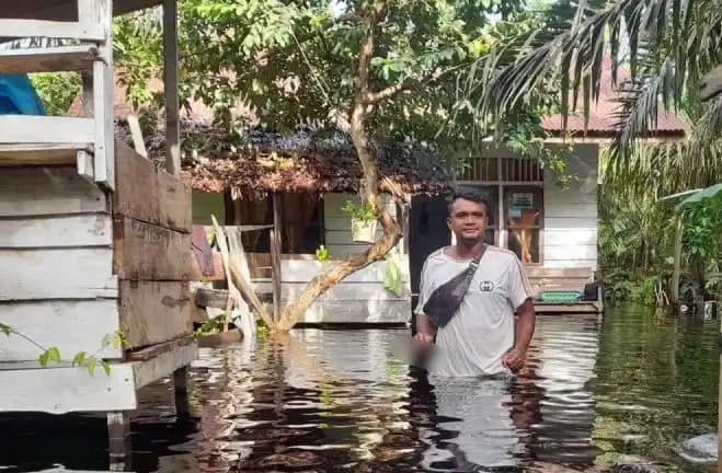 Warga Kecamatan Arongan Lambalek, Kabupaten Aceh Barat, melintasi genangan banjir