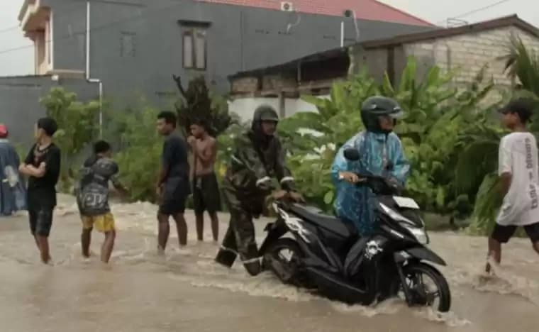 Warga membantu mendorong kendaraan melintasi genangan air