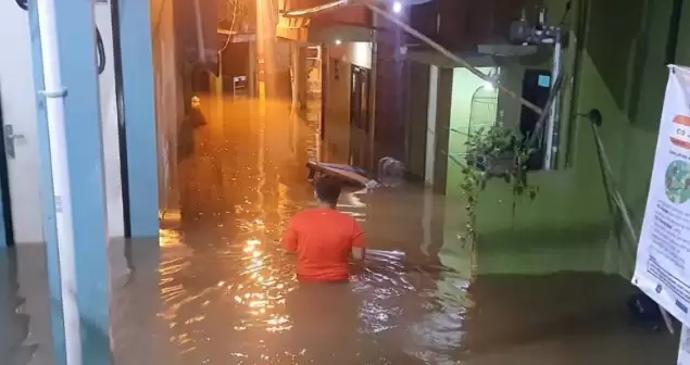 Salah satu warga tengah melintasi jalan yang terendam banjir di kawasan Kebon Pala, Kelurahan Kampung Melayu, Kecamatan Jatinegara, Jakarta Timur, Jumat (15/3/2024) dini hari (15/3/2024). [Foto: Ist]