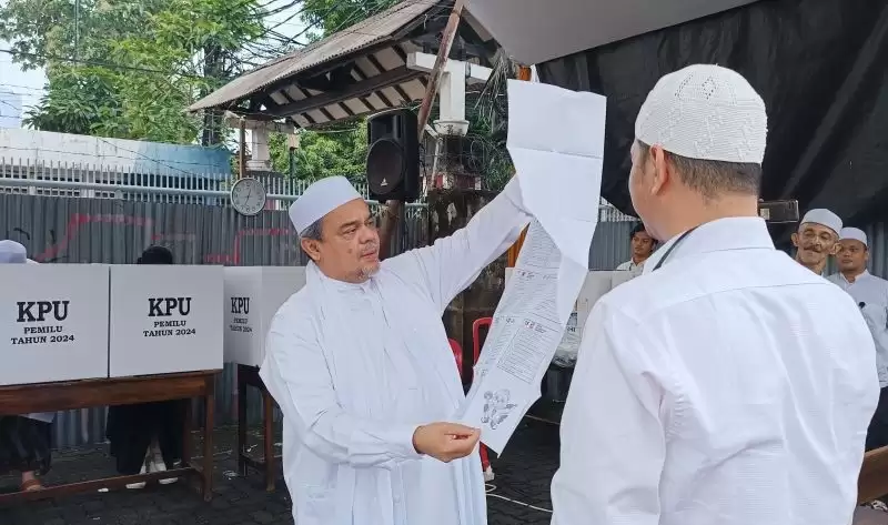 Muhammad Rizieq Shihab (kiri) mengecek surat suara ketika akan menyalurkan hak suaranya di TPS 47 Petamburan, Jakarta Pusat, Rabu (14/2). [Foto: ANTARA/Khaerul Izan]