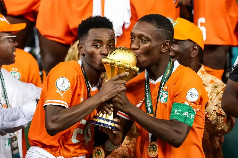 Pemain Pantai Gading, Max-Alain Gradel dan Simon Adingra mencium trofi Piala Afrika 2023. (Foto: AFP/FRANCK FIFE)