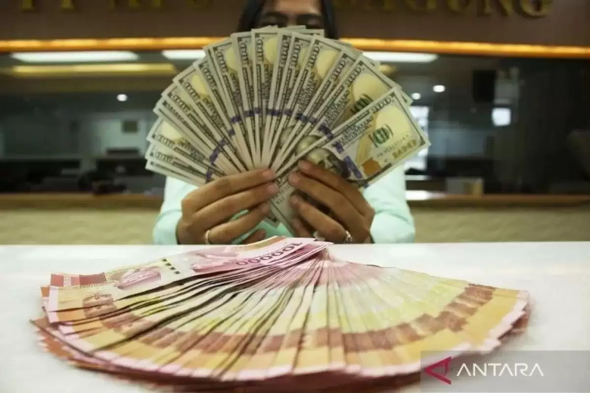 Teller memegang mata uang Dolar AS dan Rupiah di sebuah tempat penukaran uang (Foto: Antara)