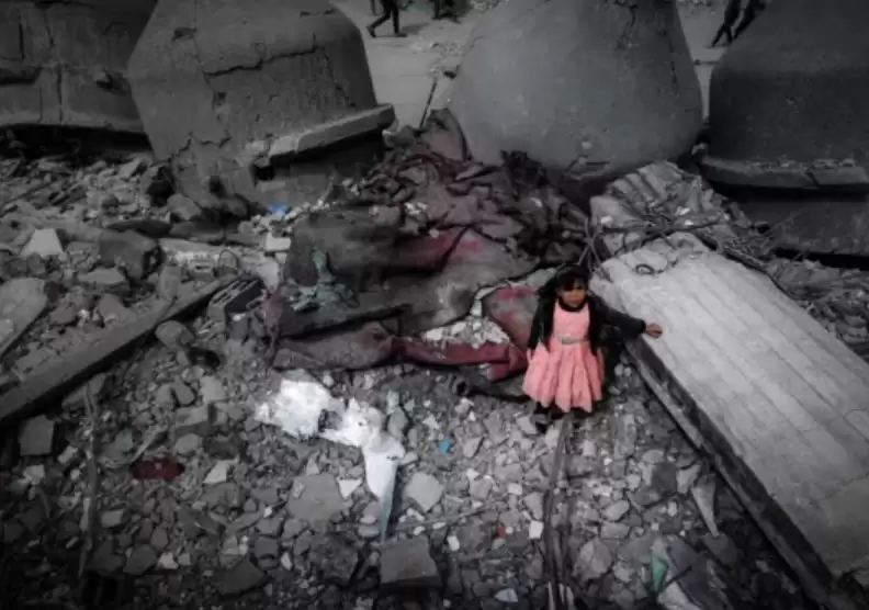 Seorang gadis Palestina mengenakan gaun merah muda berdiri di tengah reruntuhan Masjid Al-Faruq (Foto: MI Repro AFP)