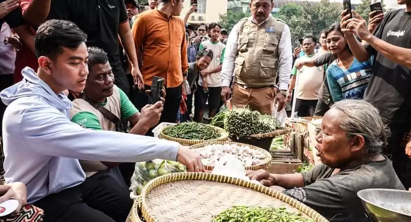 Cawapres nomor urut 2 Gibran Rakabuming Raka (kiri) berbincang dengan pedagang di los sayur mayur di Pasar Induk Kramat Jati, Jakarta, Sabtu (23/12). (Foto: ANTARA)