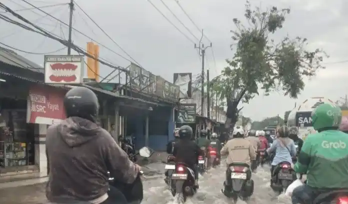 Pengendara roda dua saat melintasi jalan yang tergenang air banjir di kawasan Cikupa (Foto: Antara)