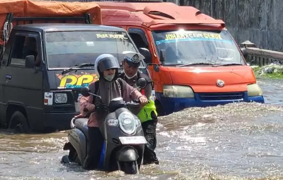 Anggota Satlantas Polrestabes Semarang, membantu seorang pengendara sepeda motor yang terjebak banjir di sekitar Jalan Kaligawe Semarang, Jawa Tengah, Sabtu (6/4/2024). [Foto: ANTARA}