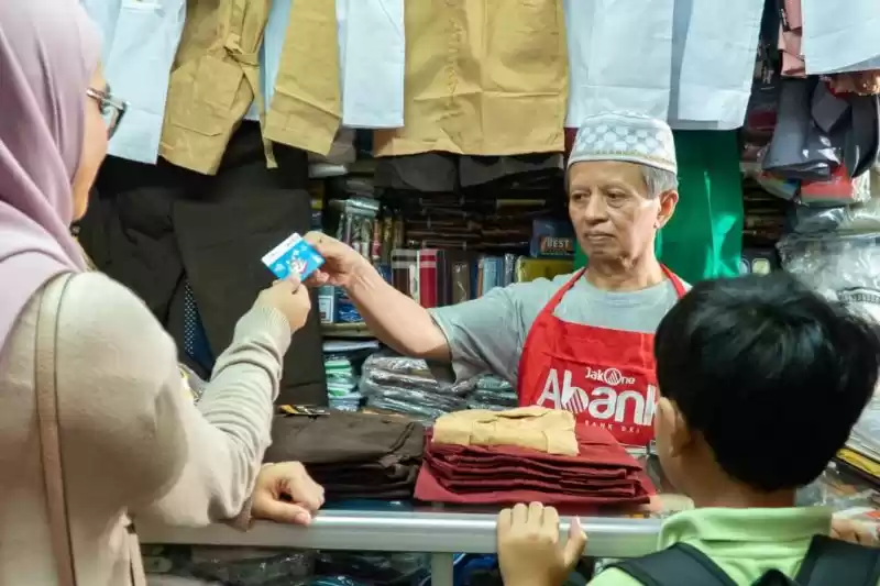 Pedagang pakaian yang juga Agen JakOne Abank, tengah melayani transaksi dengan orang tua murid pemegang Kartu Jakarta Pintar Plus di Pasar Santa, Jakarta Selatan, Selasa (30/4/2024). [Foto: Bank DKI]