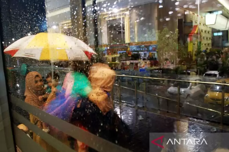 Warga menggunakan payung ketika hujan deras (Foto: ANTARA)