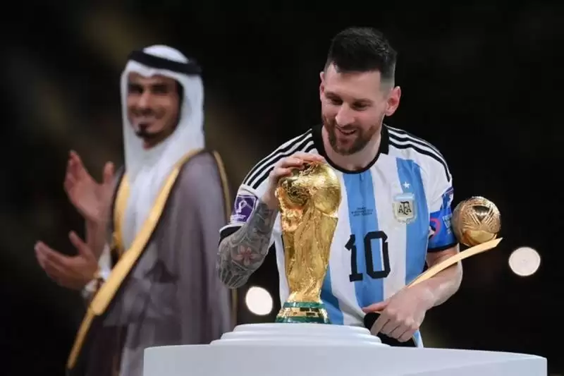 Mega bintang Argentina Lionel Messi menyentuh trofi Piala Dunia setelah menerima anugerah Pemain Terbaik di Piala Dunia 2022 Qatar (Foto: FRANCK FIFE/AFP)