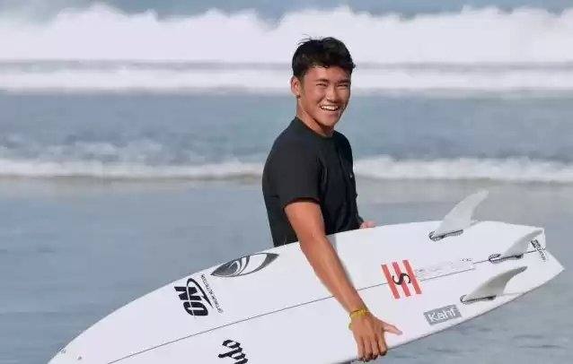 Atlet selancar ombak Indonesia Rio Waida membawa papan surfing. (Foto: Antara)