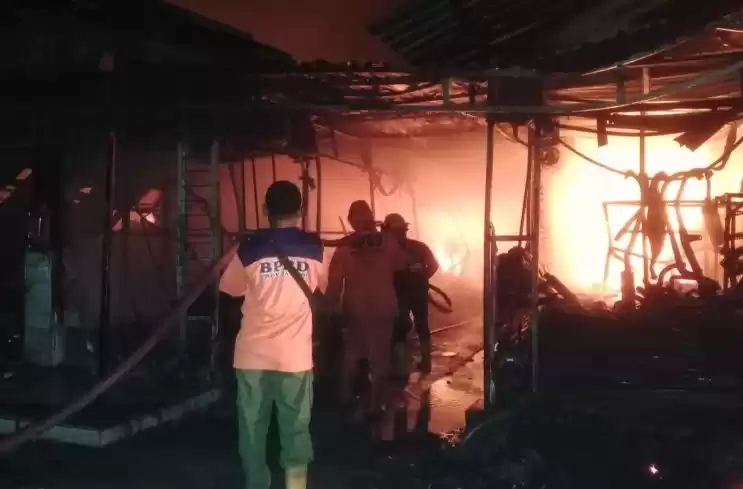 Petugas pemadam kebakaran berjuang memadamkan api yang membakar los pedagang di pasar barang bekas di Jalan Kudus.(Foto: Antara)