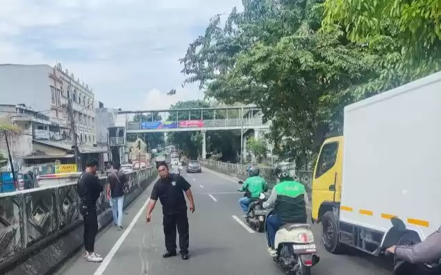 Petugas menunjukan lokasi kecelakaan antara sepeda motor ojek daring dengan truk boks. (Foto: Antara)