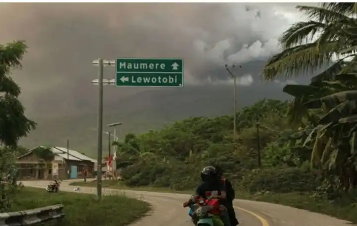 Pengendara Motor latar belakang Gunung Lewotobi Laki-Laki (Foto: Antara)