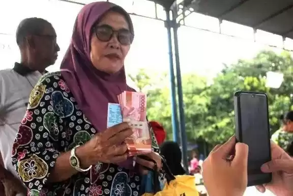 Petugas memotret warga dari keluarga penerima manfaat mengambil Bantuan Langsung Tunai (BLT) saat penyaluran bantuan sosial tahap II di Medan, Sumatera Utara, Minggu (3/12/2023).