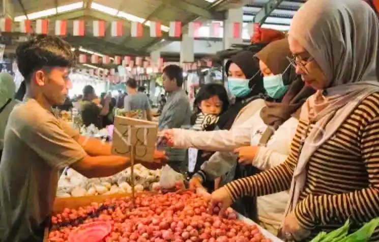 Seorang pedagang bawang merah dan bawang putih melayani pembeli di Pasar Flamboyan. (Foto: Antara)