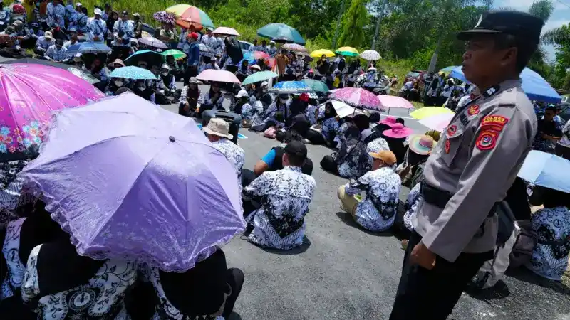 Seorang aparat kepolisian berdiri di antara sejumlah guru di depan Pengadilan Negeri Konawe Selatan saat aksi solidaritas untuk Supriyani, Senin (28/10/2024)
