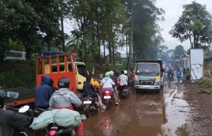 Sejumlah kendaraan melintasi jalan berlumpur bekas banjir di wilayah Cisurupan (Foto: Antara)