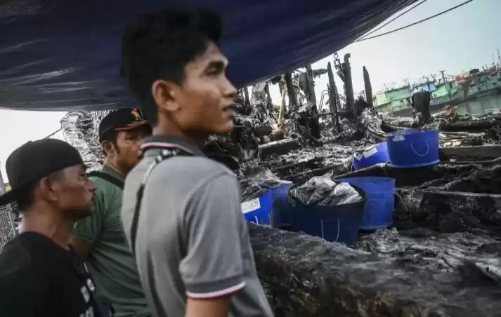 Sejumlah pekerja melihat bangkai kapal yang hangus terbakar di Pelabuhan Muara Baru. (Foto: Antara)
