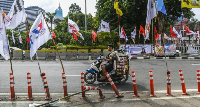 Pengendara melintas di samping alat peraga kampanye (APK) pemilu 2024 yang terpasang di pembatas jalur sepeda (stick cone) di kawasan Menteng, Jakarta, Senin (8/1/2024).(Foto: ANTARA)