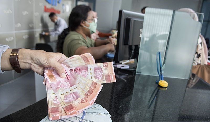 Ilustrasi - Petugas menunjukan uang pecahan rupiah dan dolar AS. (Foto: ANTARA)