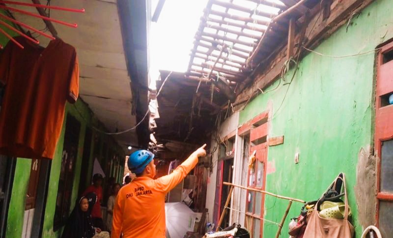 Seorang petugas BPBD DKI Jakarta sedang meninjau rumah roboh di Semanan, Kalideres, Jakarta Barat, Selasa (30/1/2024). (Foto: ANTARA)